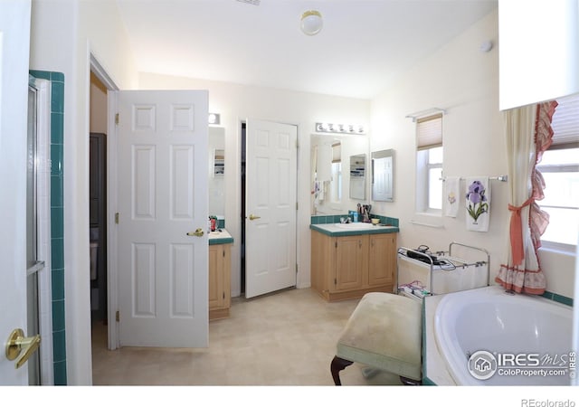 bathroom with vanity, a shower with shower door, and a bath