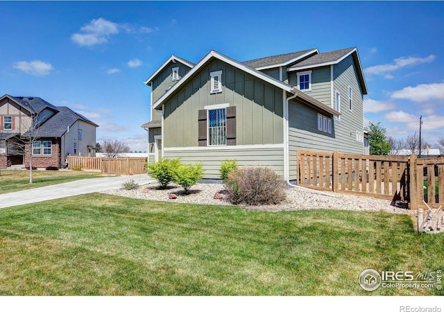 view of front of home with board and batten siding, fence, and a front yard