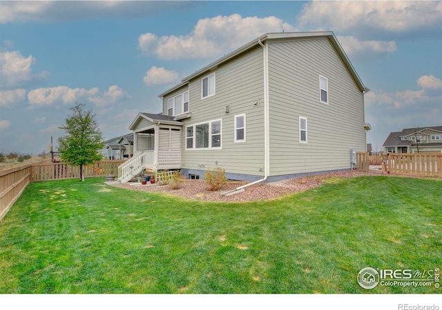 rear view of property with a lawn and a fenced backyard