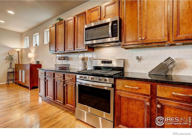 kitchen featuring appliances with stainless steel finishes, tasteful backsplash, brown cabinetry, and light wood-style flooring