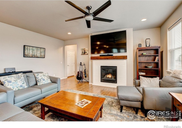 living area with a ceiling fan, a fireplace, wood finished floors, baseboards, and recessed lighting