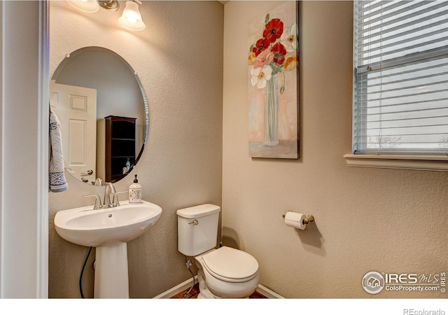 bathroom featuring a sink, baseboards, and toilet