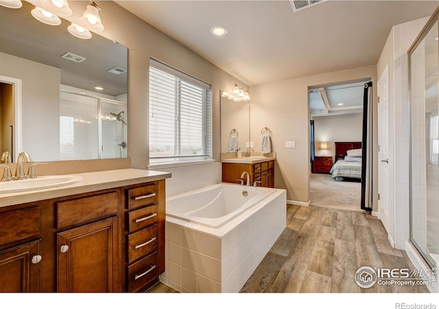 full bathroom featuring a sink, a shower stall, ensuite bath, and wood finished floors