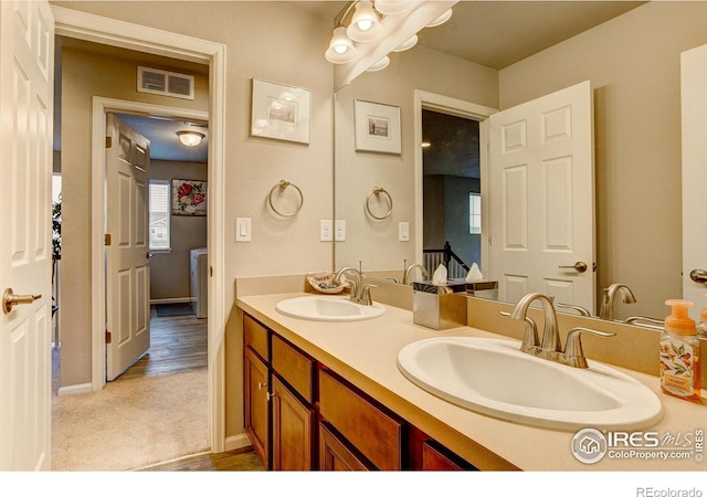 full bath with double vanity, baseboards, visible vents, and a sink