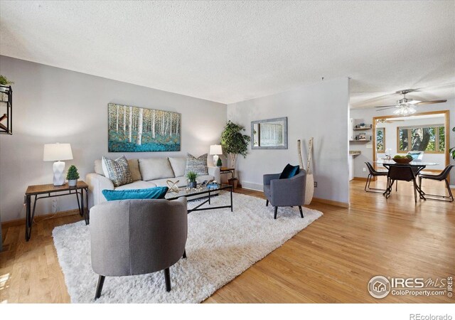 1309 Alexandria St, Lafayette, CO 80026 - living area with light wood-style flooring, a textured ceiling, a ceiling fan, and baseboards