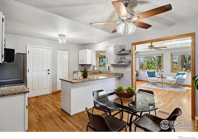 1309 Alexandria St, Lafayette, CO 80026 - kitchen with a peninsula, a sink, white cabinetry, light wood-style flooring, and freestanding refrigerator