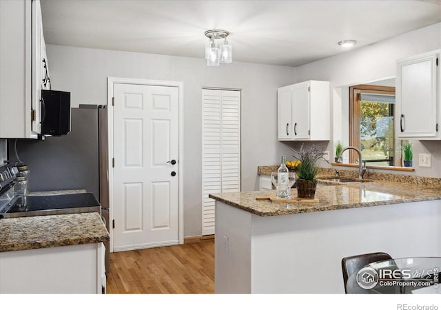 1309 Alexandria St, Lafayette, CO 80026 - kitchen with a sink, white cabinetry, light wood finished floors, and light stone countertops