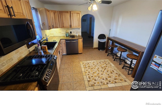 17233 County Road 16, Atwood, CO 80722 - kitchen with range with gas stovetop, decorative backsplash, arched walkways, a sink, and dishwasher