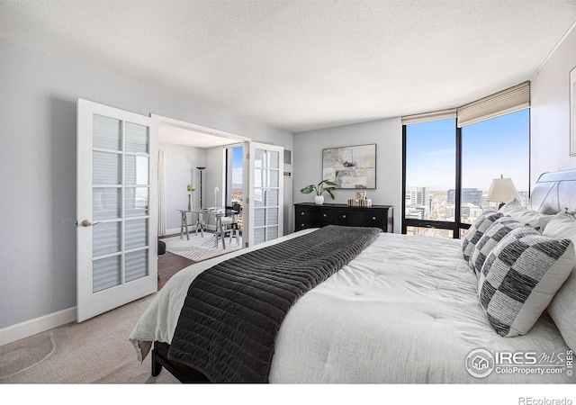 carpeted bedroom with french doors, a textured ceiling, baseboards, and multiple windows