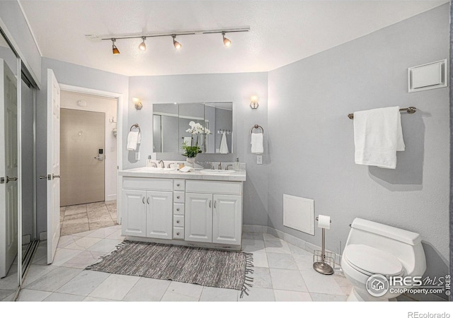 bathroom featuring double vanity, toilet, baseboards, and a sink