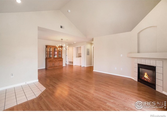 5225 White Willow Dr Unit 210, Fort Collins, CO 80528 - unfurnished living room with an inviting chandelier, high vaulted ceiling, a tiled fireplace, wood finished floors, and visible vents