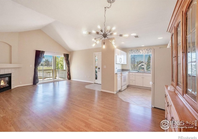 5225 White Willow Dr Unit 210, Fort Collins, CO 80528 - unfurnished living room with light wood-type flooring, a tiled fireplace, a chandelier, and a wealth of natural light