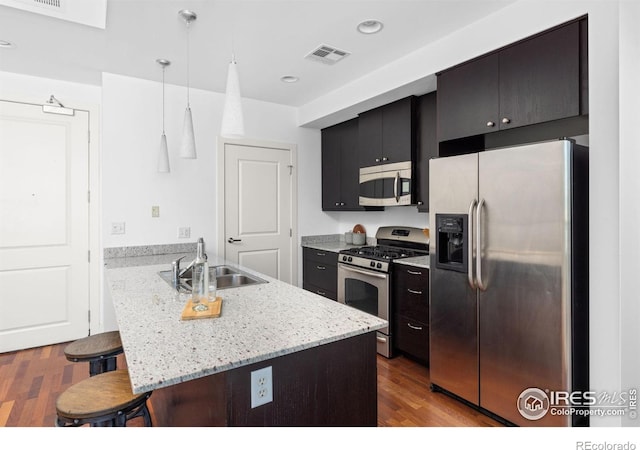 2001 Lincoln St Unit 2113, Denver, CO 80202 - kitchen with appliances with stainless steel finishes, a breakfast bar area, a peninsula, wood finished floors, and dark cabinets