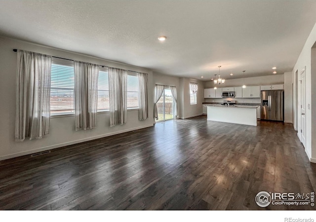 2325 Mountain Sky Dr, Fort Lupton, CO 80621 - unfurnished living room with a chandelier, dark wood-type flooring, baseboards, and recessed lighting