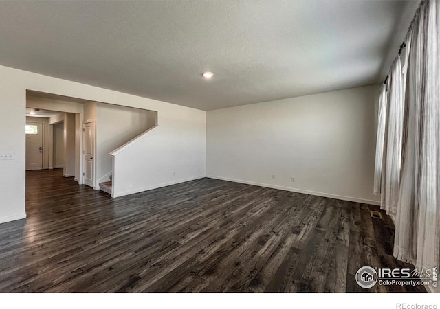 2325 Mountain Sky Dr, Fort Lupton, CO 80621 - unfurnished room featuring dark wood-type flooring, stairway, baseboards, recessed lighting, and a textured ceiling