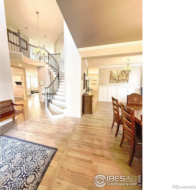 foyer entrance featuring crown molding, a notable chandelier, wood finished floors, a towering ceiling, and stairway