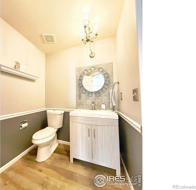 bathroom featuring vanity, toilet, baseboards, wood finished floors, and visible vents