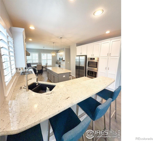 kitchen featuring a kitchen island, stainless steel appliances, white cabinets, and a sink