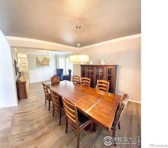 dining room featuring light wood-type flooring, baseboards, crown molding, and an inviting chandelier