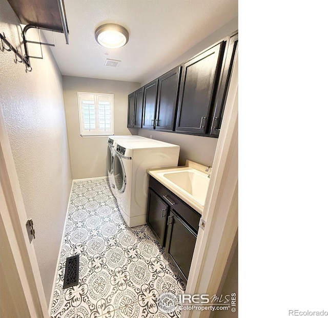 laundry room featuring visible vents, baseboards, washing machine and clothes dryer, a sink, and cabinet space