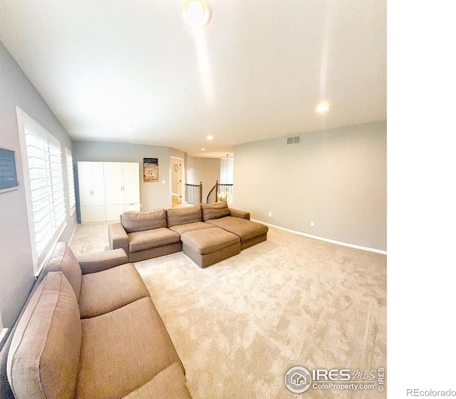 carpeted living area with recessed lighting, baseboards, visible vents, and stairway