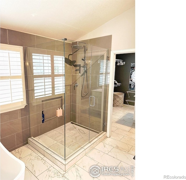 bathroom with vaulted ceiling, a walk in closet, marble finish floor, and a stall shower