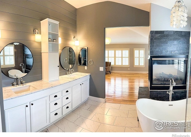 bathroom with baseboards, a sink, marble finish floor, and a soaking tub