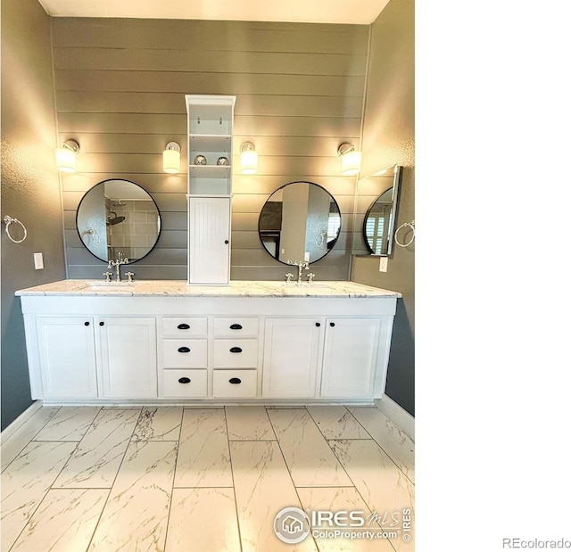 bathroom with double vanity, baseboards, and marble finish floor
