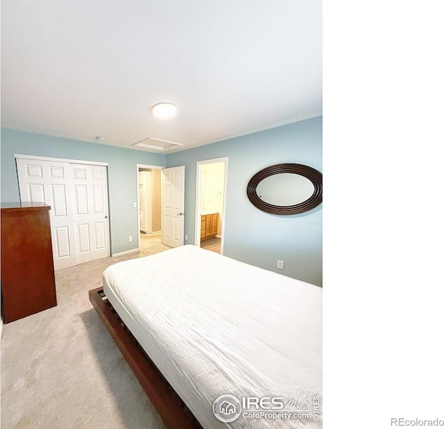 carpeted bedroom featuring a closet, attic access, and connected bathroom