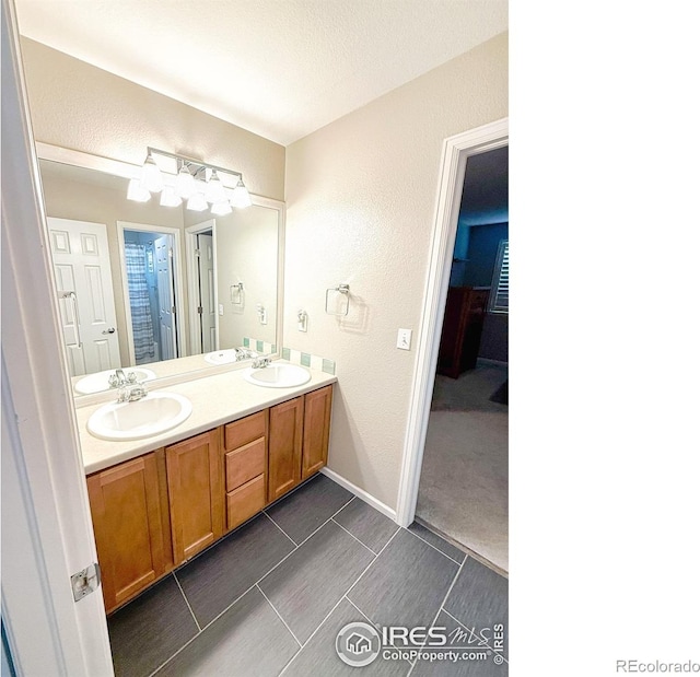 bathroom with a sink, a textured wall, and double vanity
