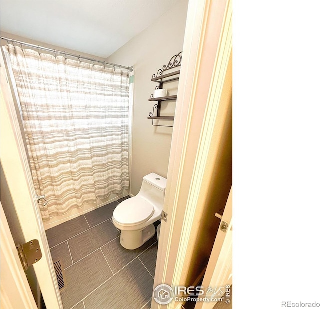 full bath with toilet and a shower with curtain