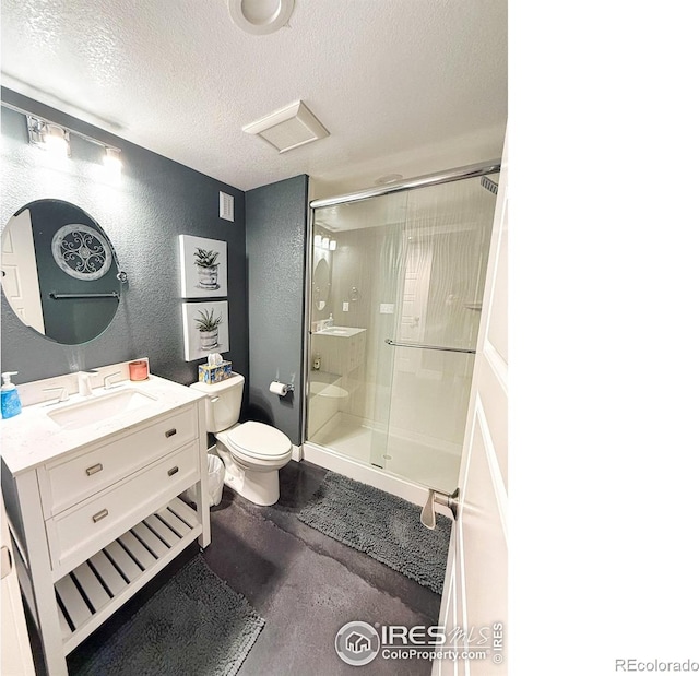 bathroom featuring vanity, a textured wall, toilet, a textured ceiling, and a stall shower