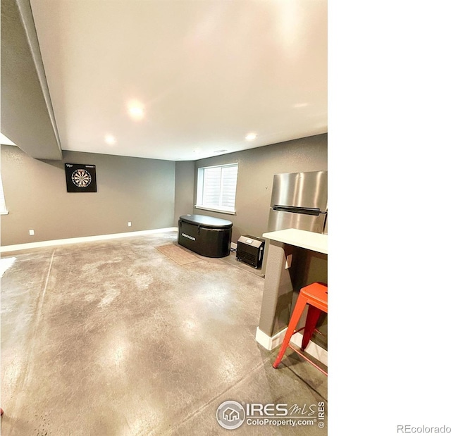 below grade area with baseboards, recessed lighting, and freestanding refrigerator