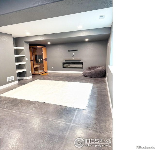 living area with visible vents, baseboards, and concrete flooring