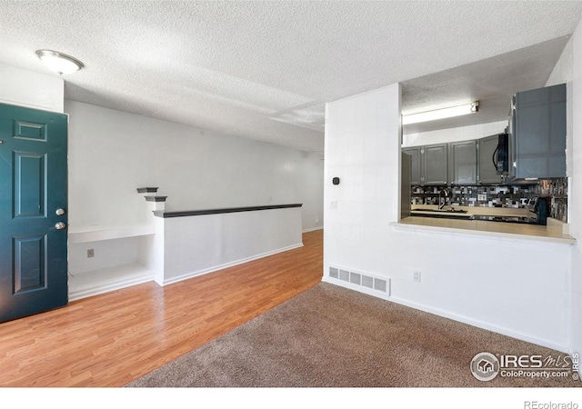 interior space with visible vents, a textured ceiling, and wood finished floors