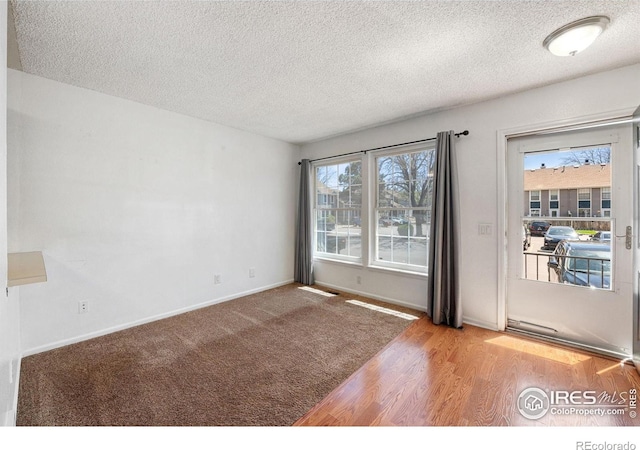 spare room with a textured ceiling, wood finished floors, and a healthy amount of sunlight