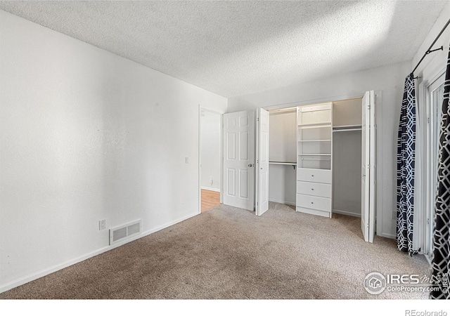 unfurnished bedroom featuring baseboards, carpet flooring, a textured ceiling, and visible vents