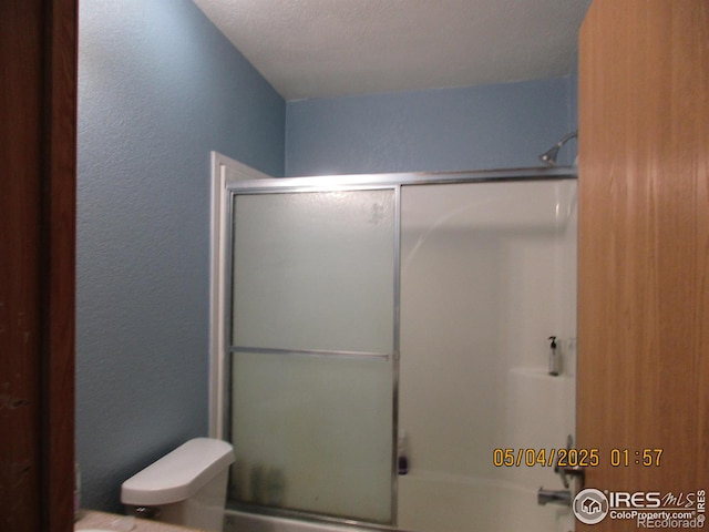 9021 County Road U.5, Weldona, CO 80653 - full bathroom with a textured wall, toilet, and bath / shower combo with glass door