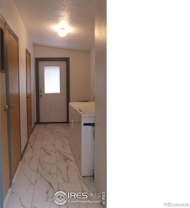 9021 County Road U.5, Weldona, CO 80653 - washroom featuring washer and clothes dryer, light marble finish flooring, and a textured ceiling