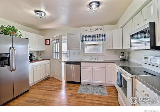 kitchen featuring light wood-type flooring, white cabinets, appliances with stainless steel finishes, and a sink