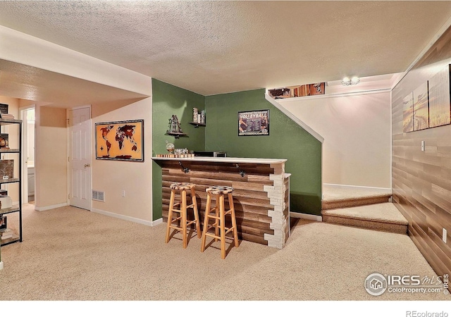 bar with a textured ceiling, a bar, visible vents, and carpet
