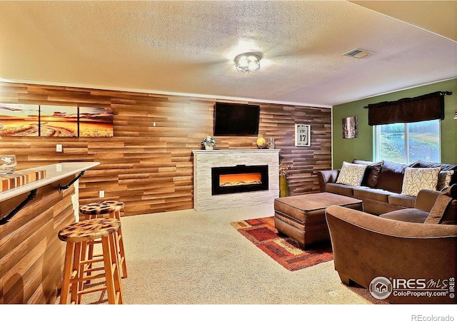 living room with a fireplace, a textured ceiling, carpet, and visible vents
