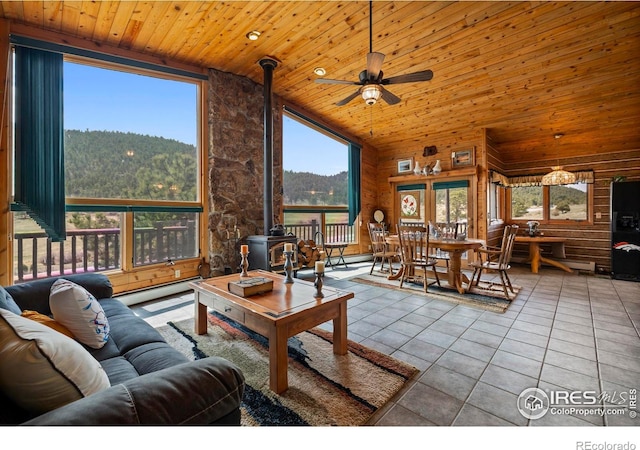 living area with wooden ceiling, a baseboard heating unit, ceiling fan, tile patterned floors, and a wood stove