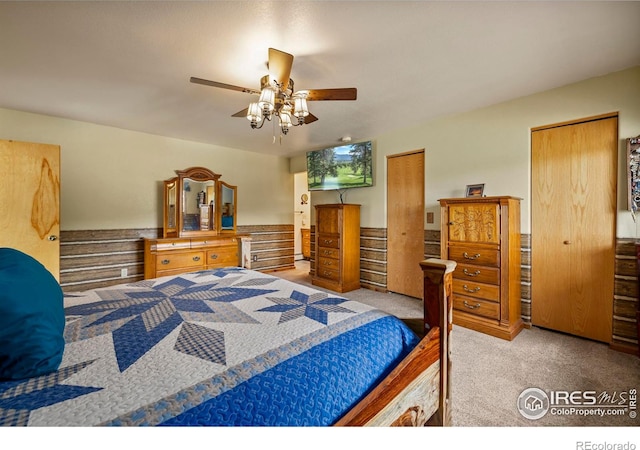 bedroom with ceiling fan, carpet flooring, and two closets