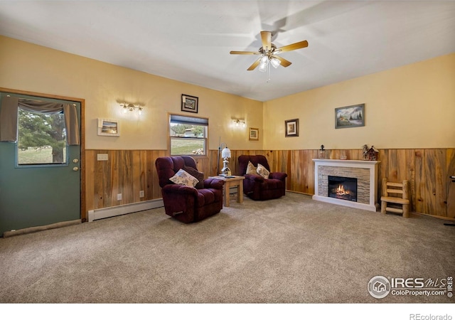 living room featuring a baseboard heating unit, a healthy amount of sunlight, wood walls, and wainscoting