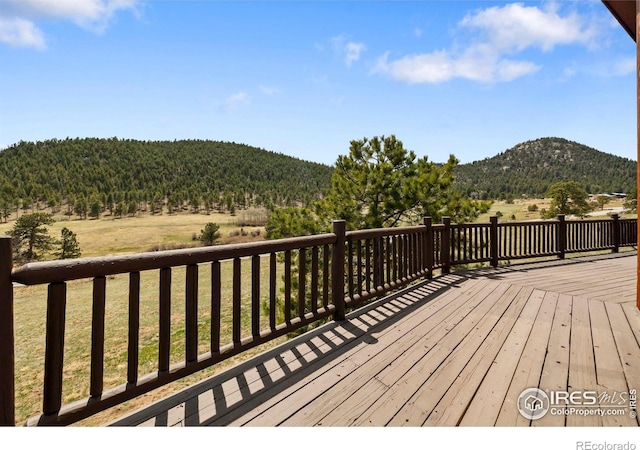 deck featuring a lawn, a wooded view, and a mountain view