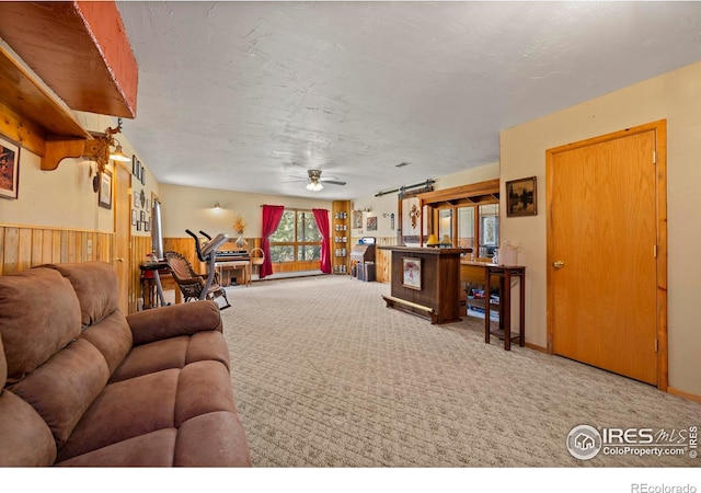 living room with ceiling fan, wood walls, a wealth of natural light, and carpet