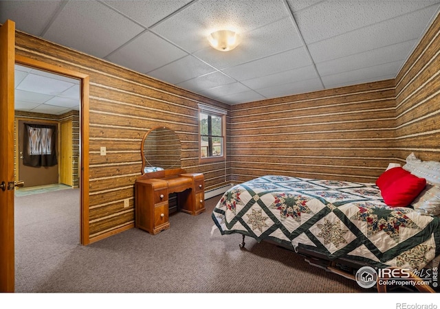 carpeted bedroom featuring wood walls, baseboard heating, and a paneled ceiling