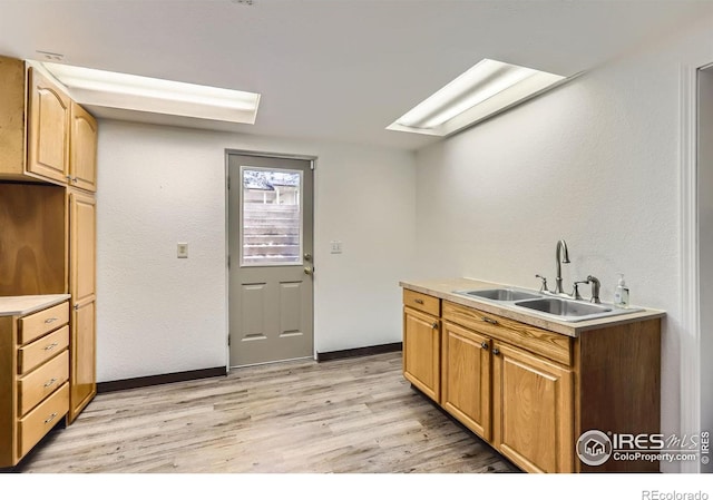1720 Chaparro Cir, Berthoud, CO 80513 - kitchen with a sink, a skylight, light wood-type flooring, baseboards, and light countertops
