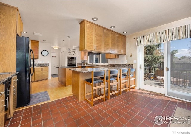 kitchen with a peninsula, brown cabinets, black appliances, visible vents, and recessed lighting